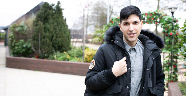 man standing in a courtyard wearing a coat