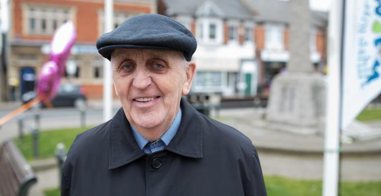 An elderly man wearing a hat smiling at the camera