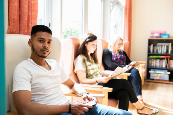 Three people sitting in some chairs in a waiting area